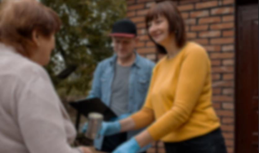 a woman handing tinned food to another woman