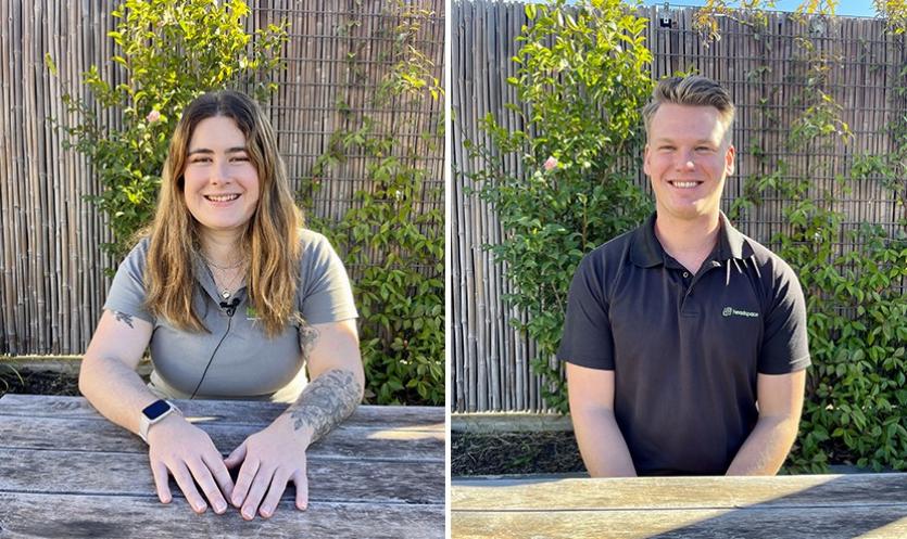 a girl sits on the left and a man on the right. Both in front of a green shrub.