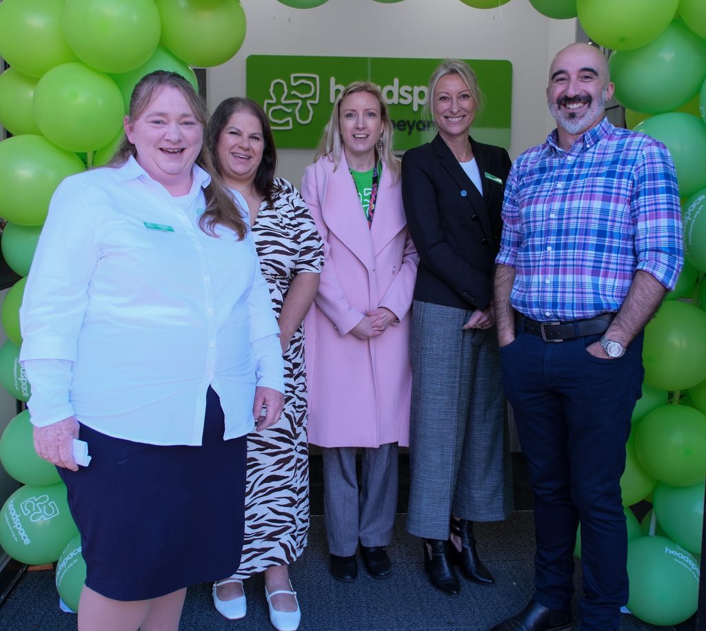 5 headspace staff standing under an arch of green balloons