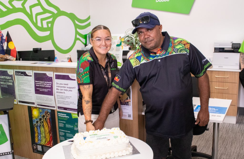 Two people stand ready to cut the cake. 