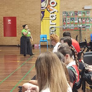 Clare stands at the front of the school hall and addresses the audience.