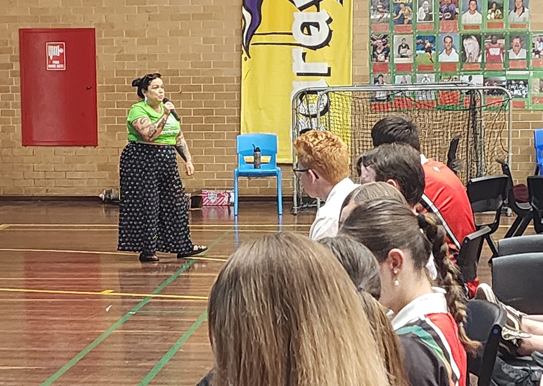 Clare stands at the front of the school hall and addresses the audience.