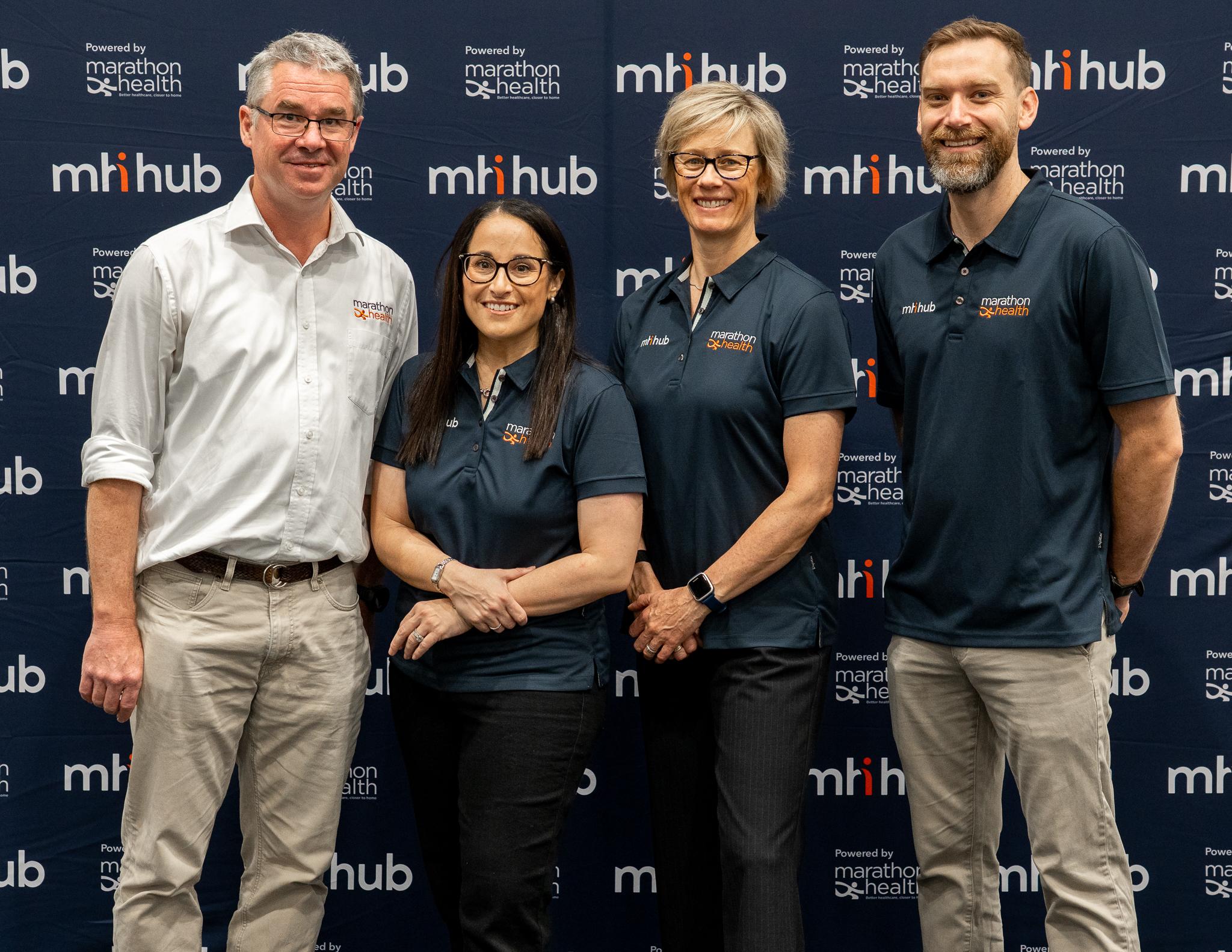 Matt, Kylie, Clare and Ash pose for the camera in front of a mhi hub branded backdrop