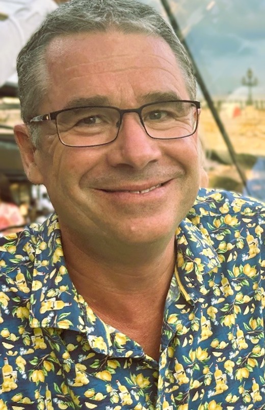Matt wears a patterned shirt and is smiling at the camera